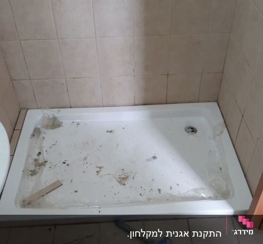 מגש מקלחת מלוכלך עם כלי עבודה על הרצפה